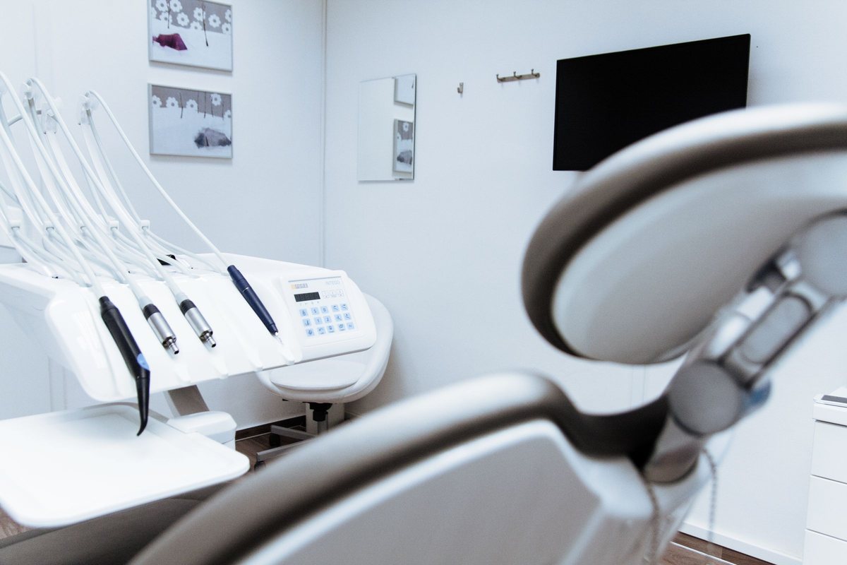 Close-up of a modern dental chair with its instrument arm and delivery unit in a bright treatment room.